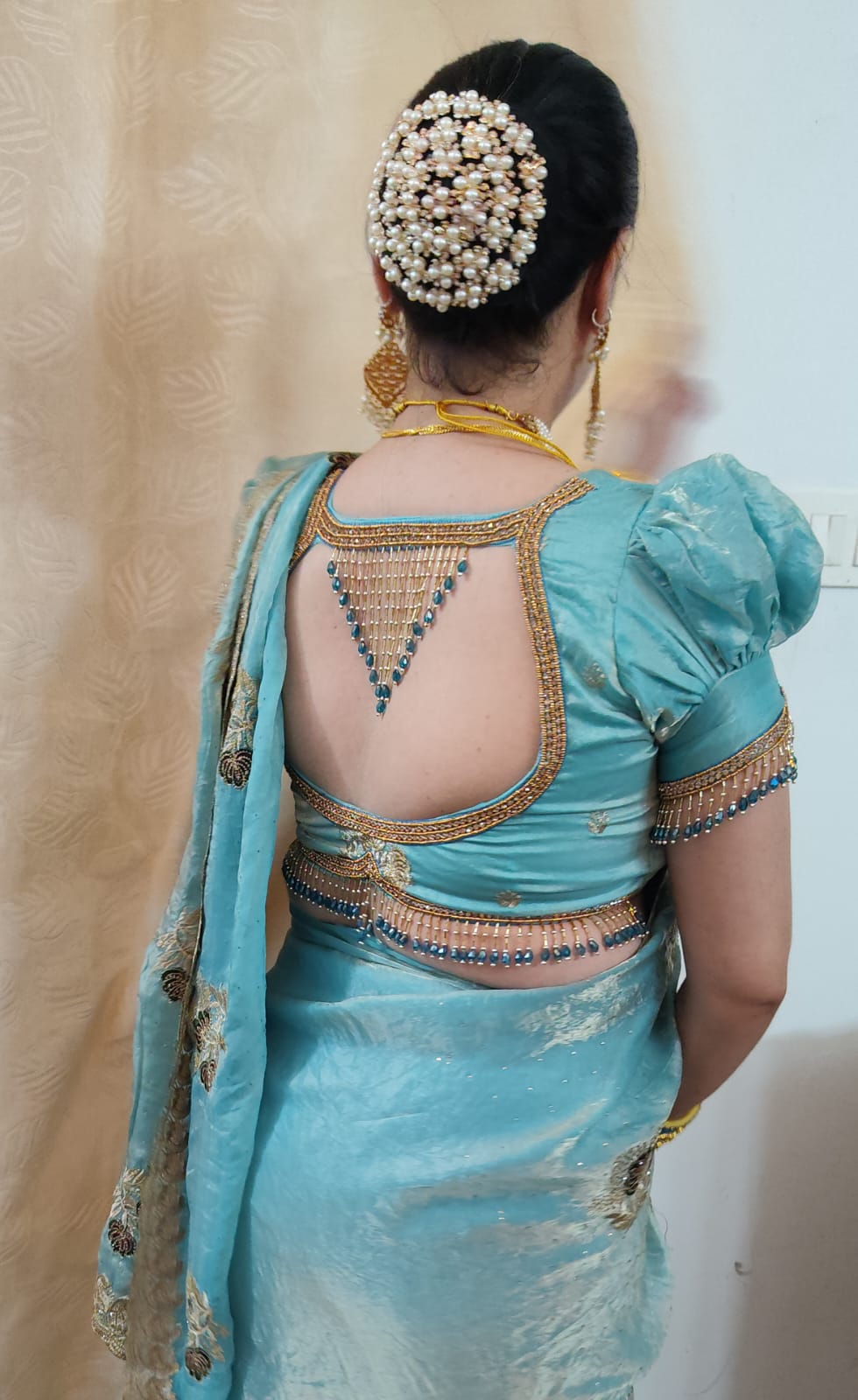 An open blouse back with a triangular fall of beads and a gold zari scalloped border